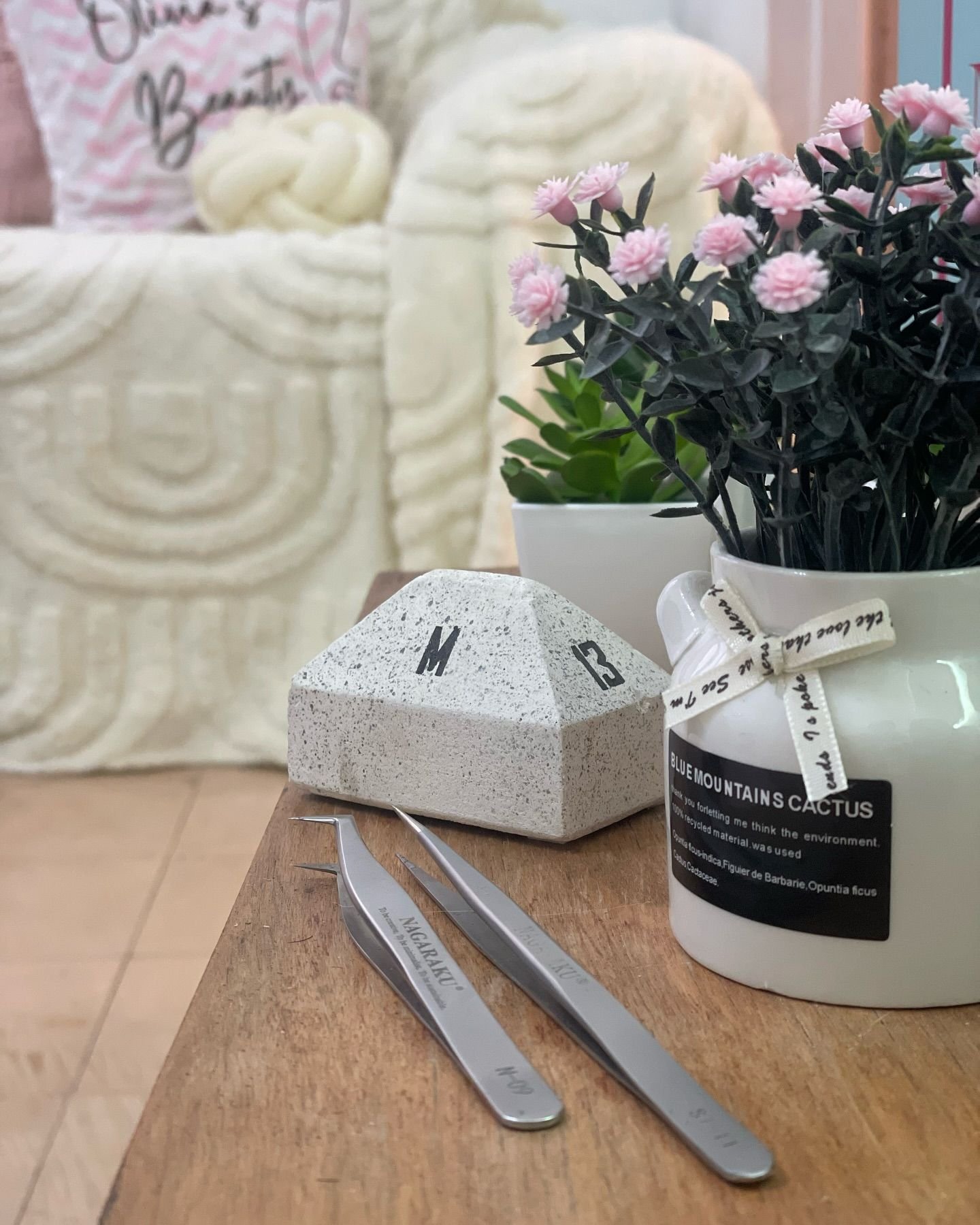 Pinzas de pestañas y flores rosadas en el estudio de Olivia's Beauty