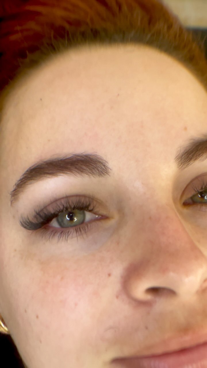 Clienta de ojos verdes con extensiones de pestañas y cejas definidas
